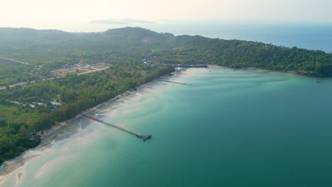 panoramic aerial overview of sloping sandy beach with piers stretching from forested land in koh rong island sihanoukville cambodia