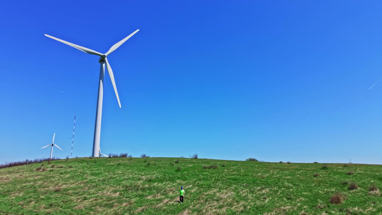 Engineer checks the operation of windmills in a field under a clear blue sky on a sunny day