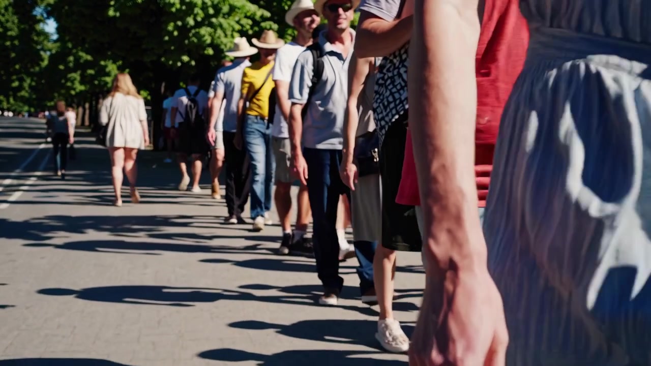 Lunga Fila di Persone che Camminano Lungo una Strada Alberata