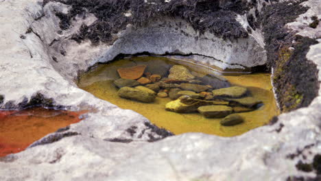 bajo ángulo medio tiro de piedra caliza agujeros de queso suizo con agua y grava en el interior