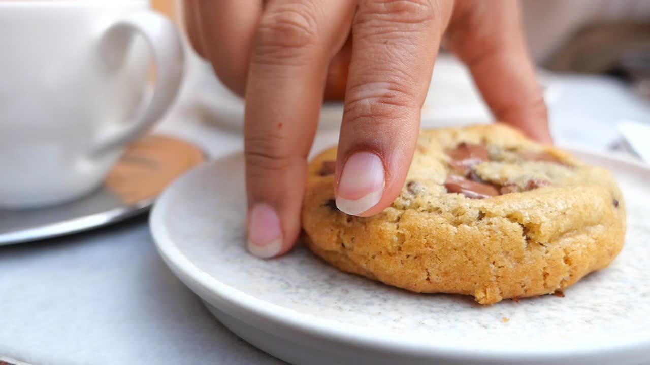 Hand Picking Up a Delicious Chocolate Chip Cookie from a Plate