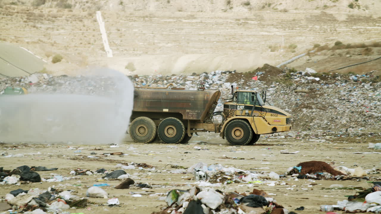 Industrial water truck spraying at a landfill