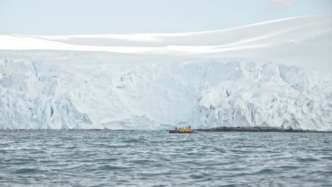 zodiac with tourists cruising in front of big glacier during antarctica tour