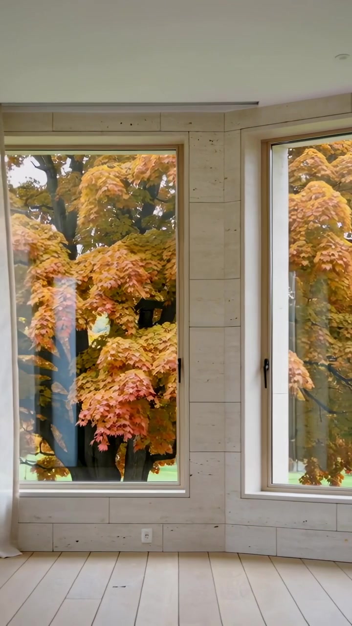 Video verticale: Tenda trasparente alle finestre mossa dalla brezza che rivela un albero di arance in una stanza rivestita in legno.