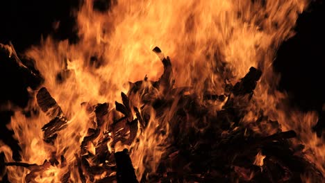 big bonfire burns at night on a black background