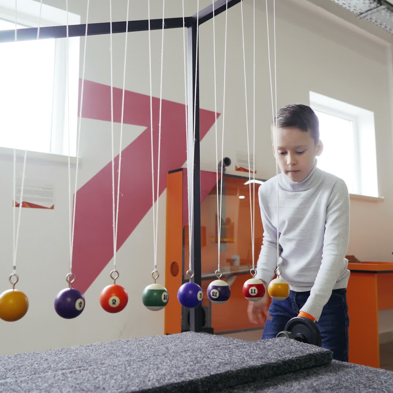 Boy makes an experiment with Newton's pendulum. The concept of physics. Museum of Science Square video