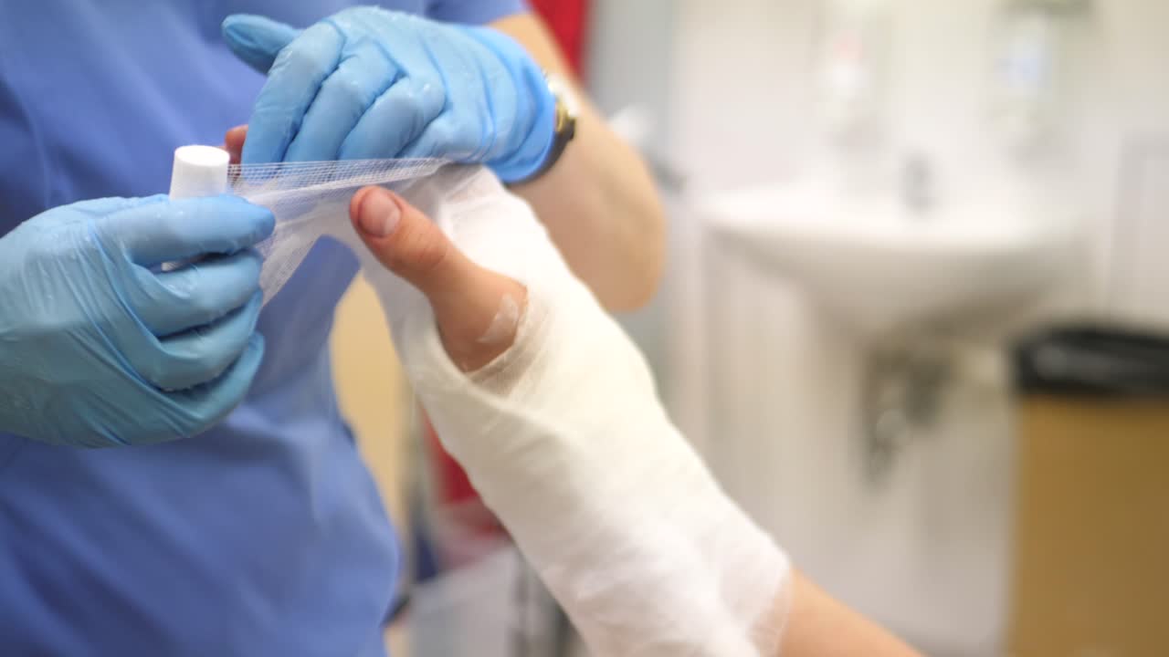 Doctor in the hospital putting on plaster on a broken arm