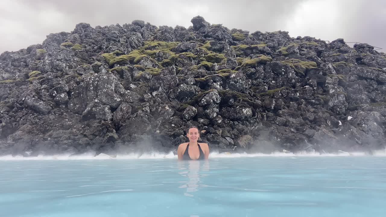 Female young tourist bathing in thermal water of Blue Lagoon in Iceland