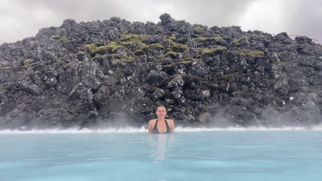 Female-young-tourist-bathing-in-thermal-water-of-Blue-Lagoon-in-Iceland