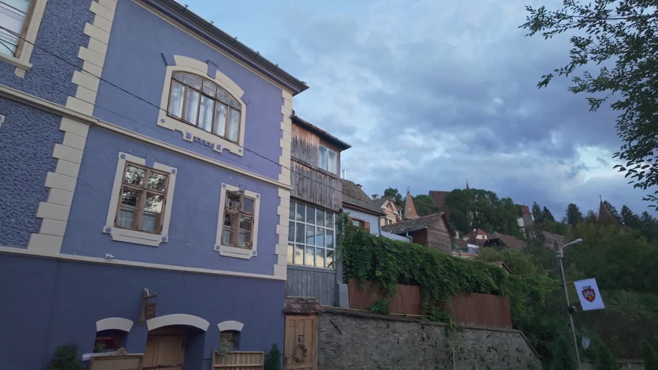 Traditional blue house facade with the green hillside of Sighișoara old town at dusk in Romania