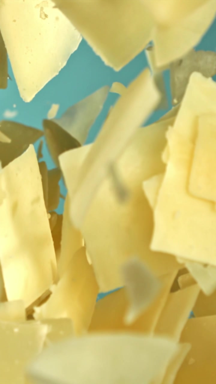 Parmesan Cheese Shavings Falling in Slow Motion on Blue Background