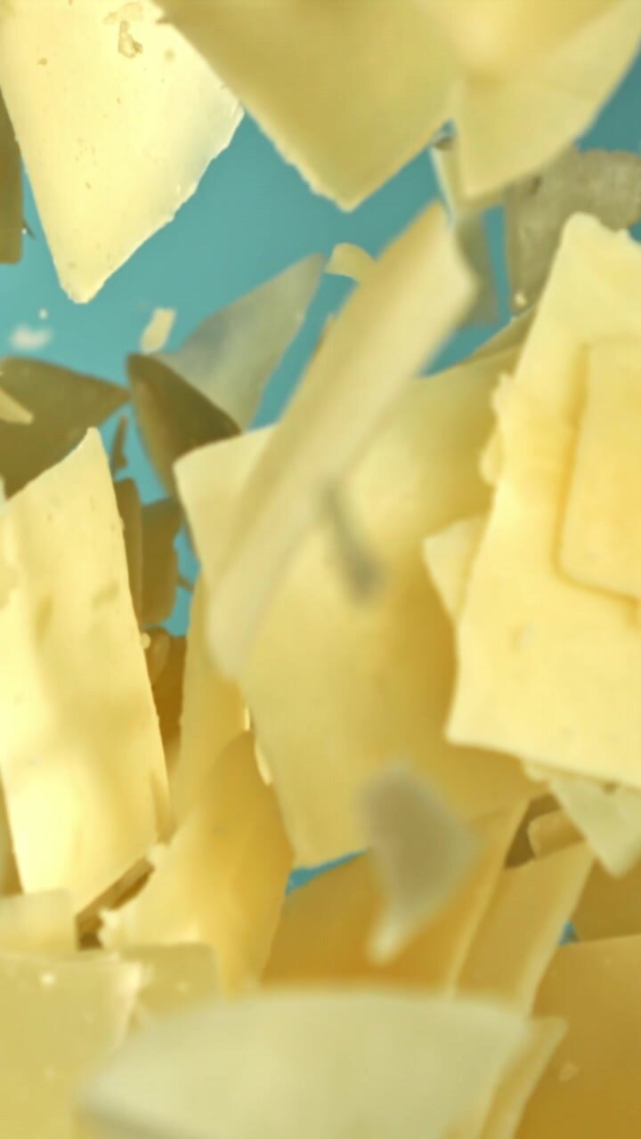 Parmesan Cheese Shavings Falling in Slow Motion on Blue Background