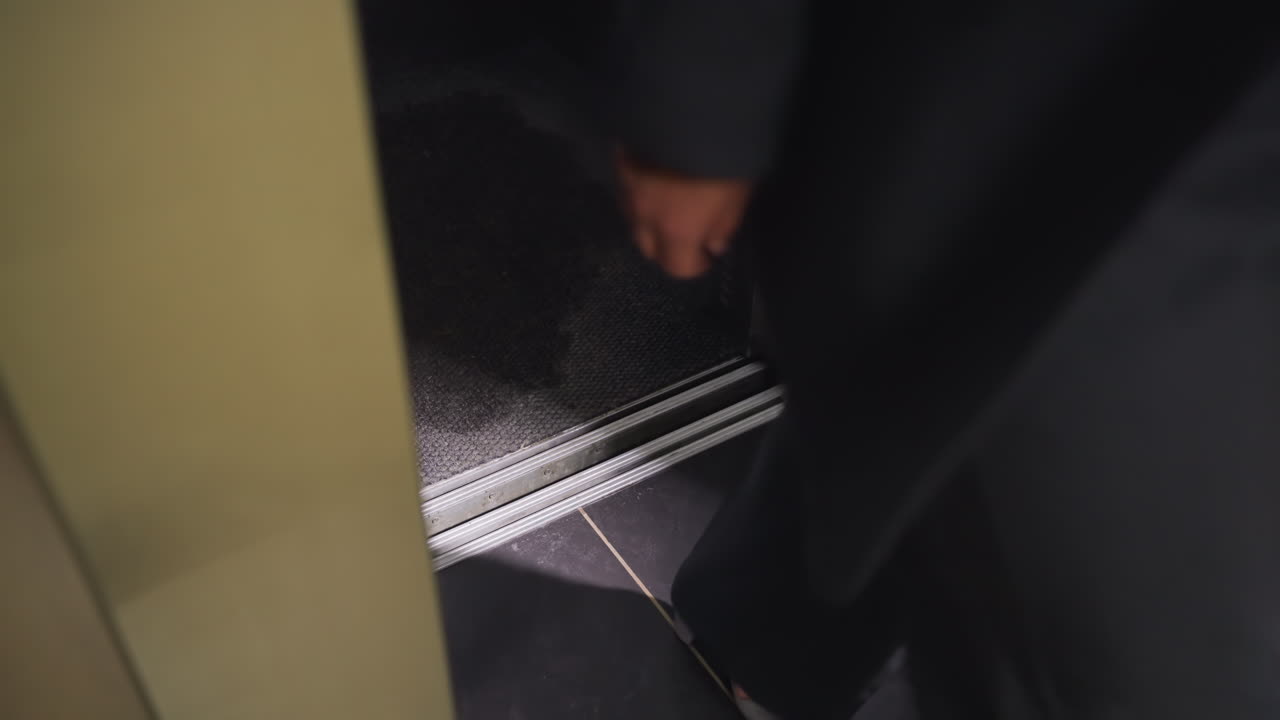 Close-up of woman's foot stepping out of elevator, professional office attire, gray high heels, corporate building, clean floor, exit from elevator, modern design, office environment