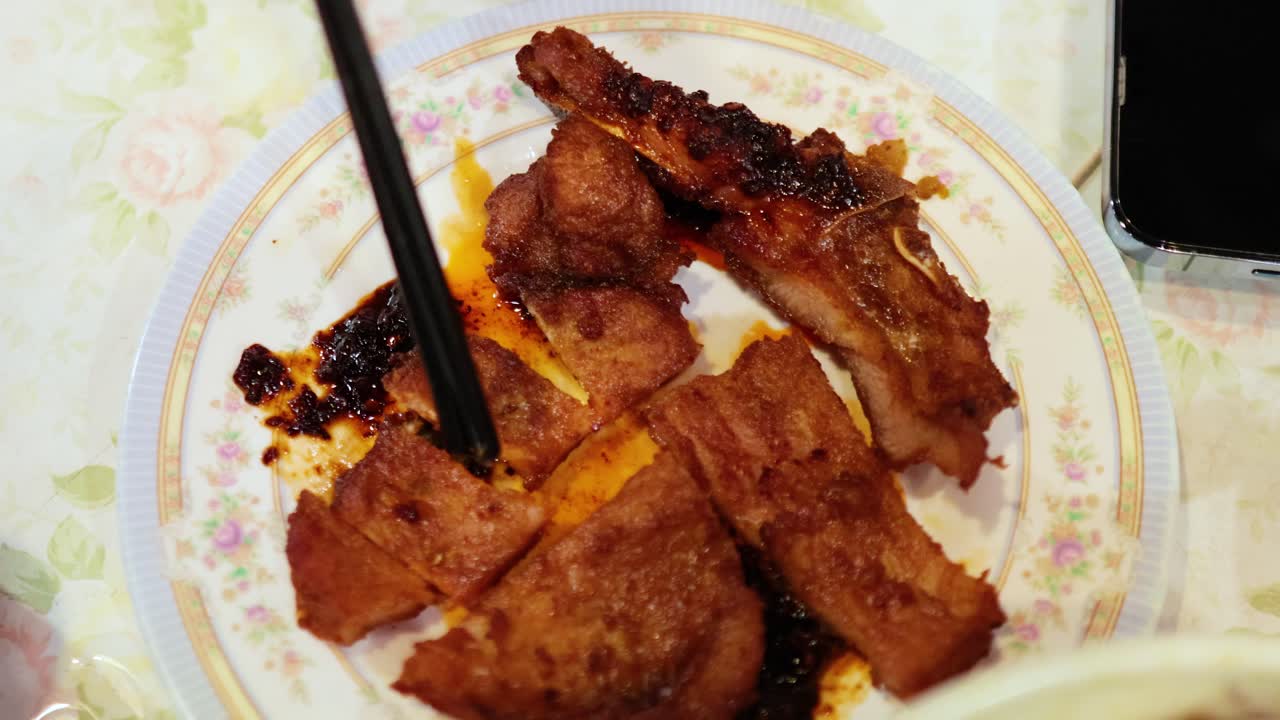 Chopsticks picking fried pork from a plate