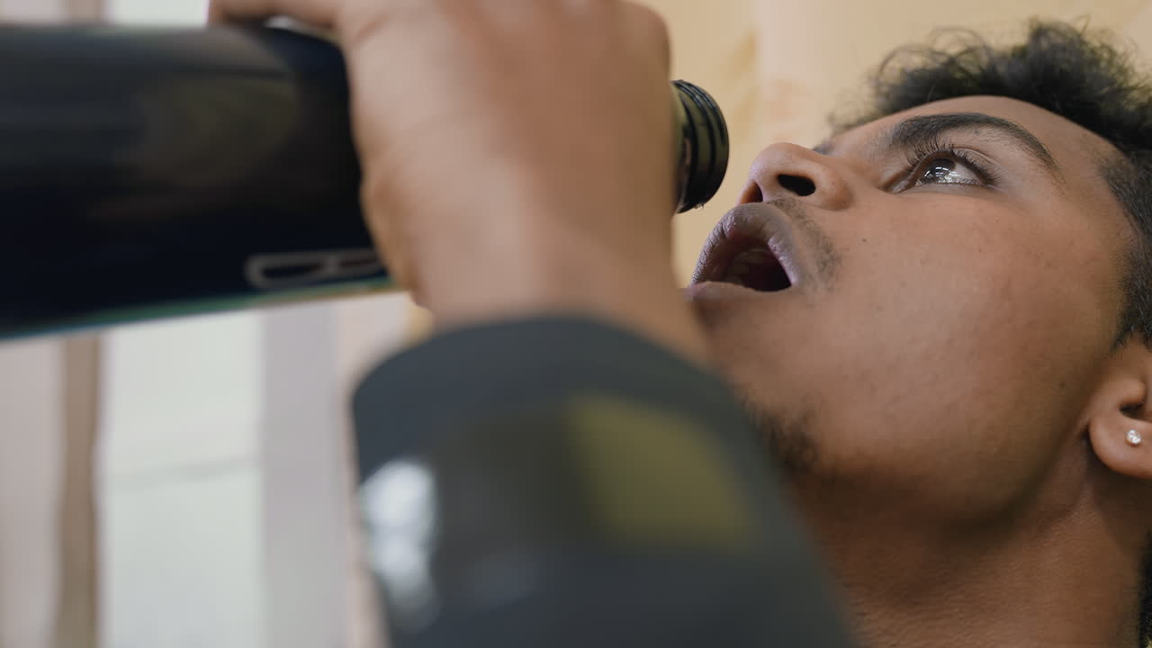 Close up of tennis player drinking water from bottle after training session, focusing on hydration, recovery, and refreshment, emphasizing importance of discipline