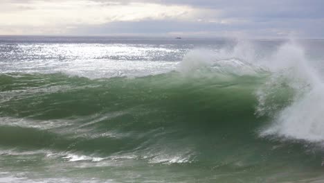 medium size wave crashing into shore as white water rushes up shoreline