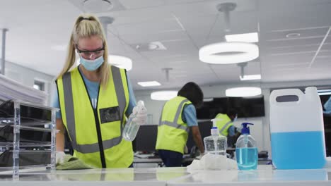 woman wearing hi vis vest and face mask cleaning the office using disinfectant