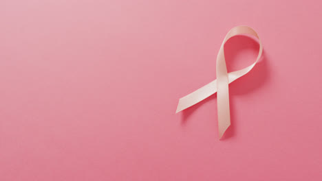 Video-of-pink-breast-cancer-ribbon-on-pale-pink-background