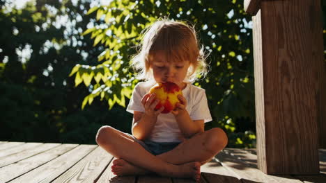 cute girl eating a peach outdoors