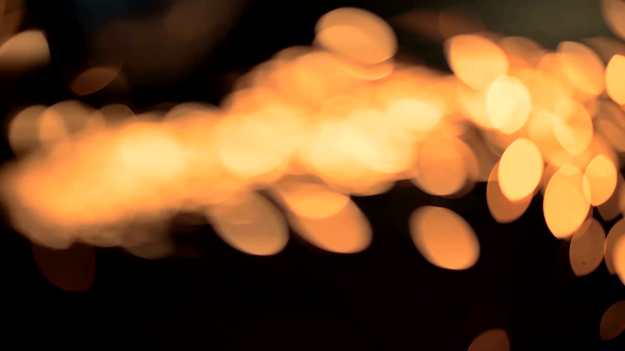 직원이 각 밀러를 사용하여 강철 파이프를 절단합니다. 보케의 불꽃은 카메라 렌즈에 바로 들어갑니다.