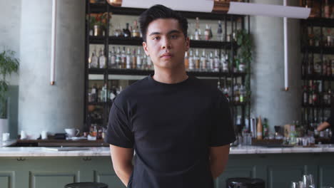 portrait of confident male owner of restaurant bar standing inside by counter