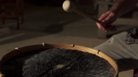 animal skin drum or bass drum being played with drumsticks