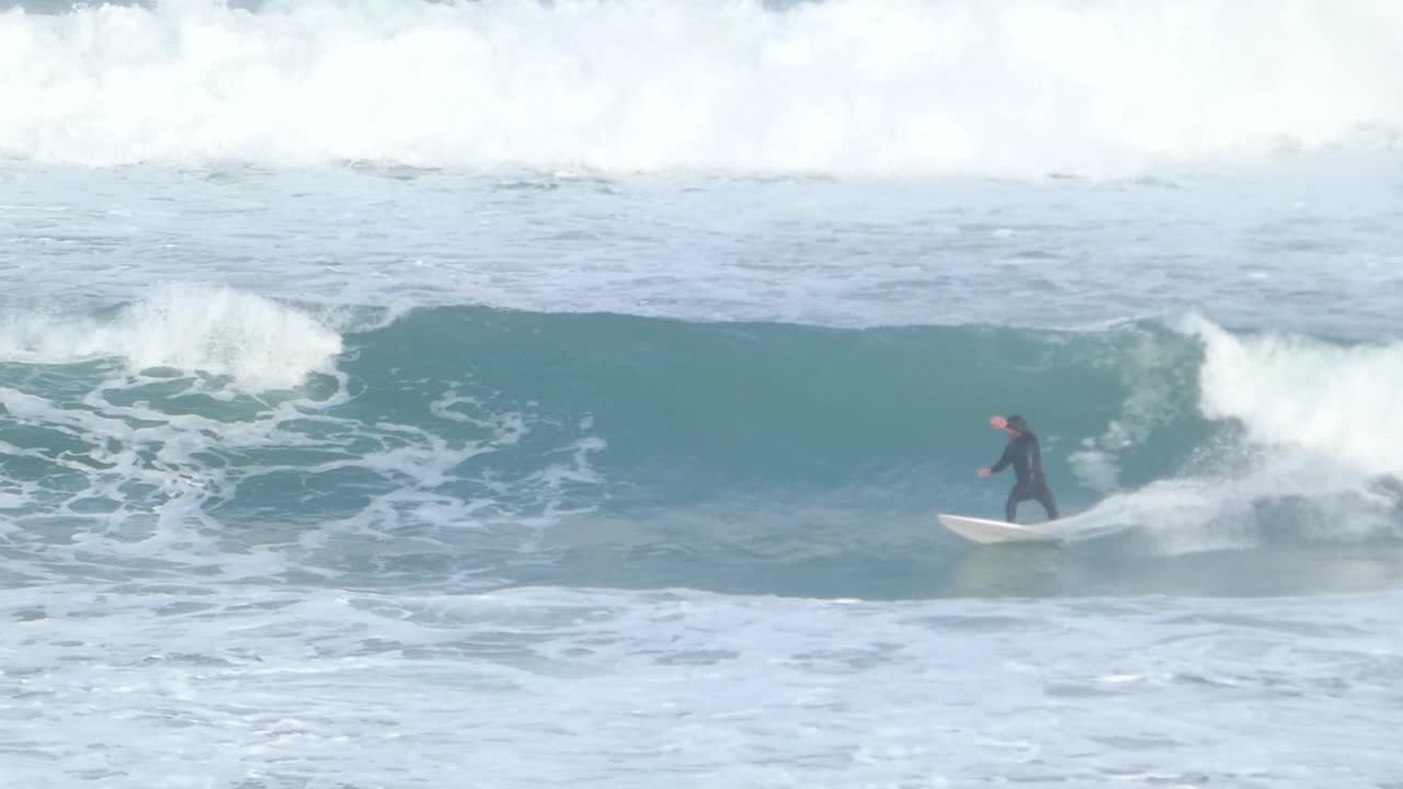 재능있는 서퍼는 상당한 물 스프레이 투사와 함께 숙련 된 뒷면 기동을 수행합니다.
