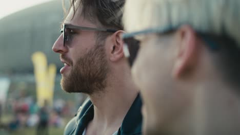 un primer plano de dos jóvenes caucásicos divirtiéndose en un festival de música mientras beben cerveza.