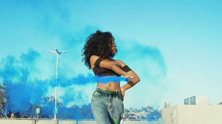 Young woman dancing outside with smoke grenade at sunset on rooftop parking garage