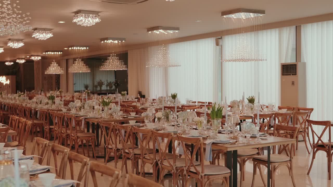 Beautifully arranged wedding hall with chandeliers and floral tables