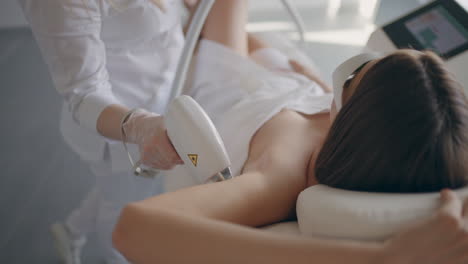 laser hair removal of armpit of female client in modern beauty salon young woman is lying in cosmetology parlour