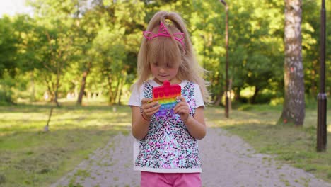 Children-girl-squeezing-presses-colorful-anti-stress-touch-screen-push-pop-it-popular-toy-in-park