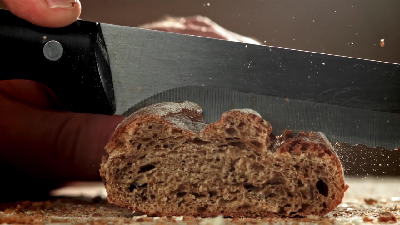 Slow Motion Close-Up of a Knife Slicing Fresh Bread