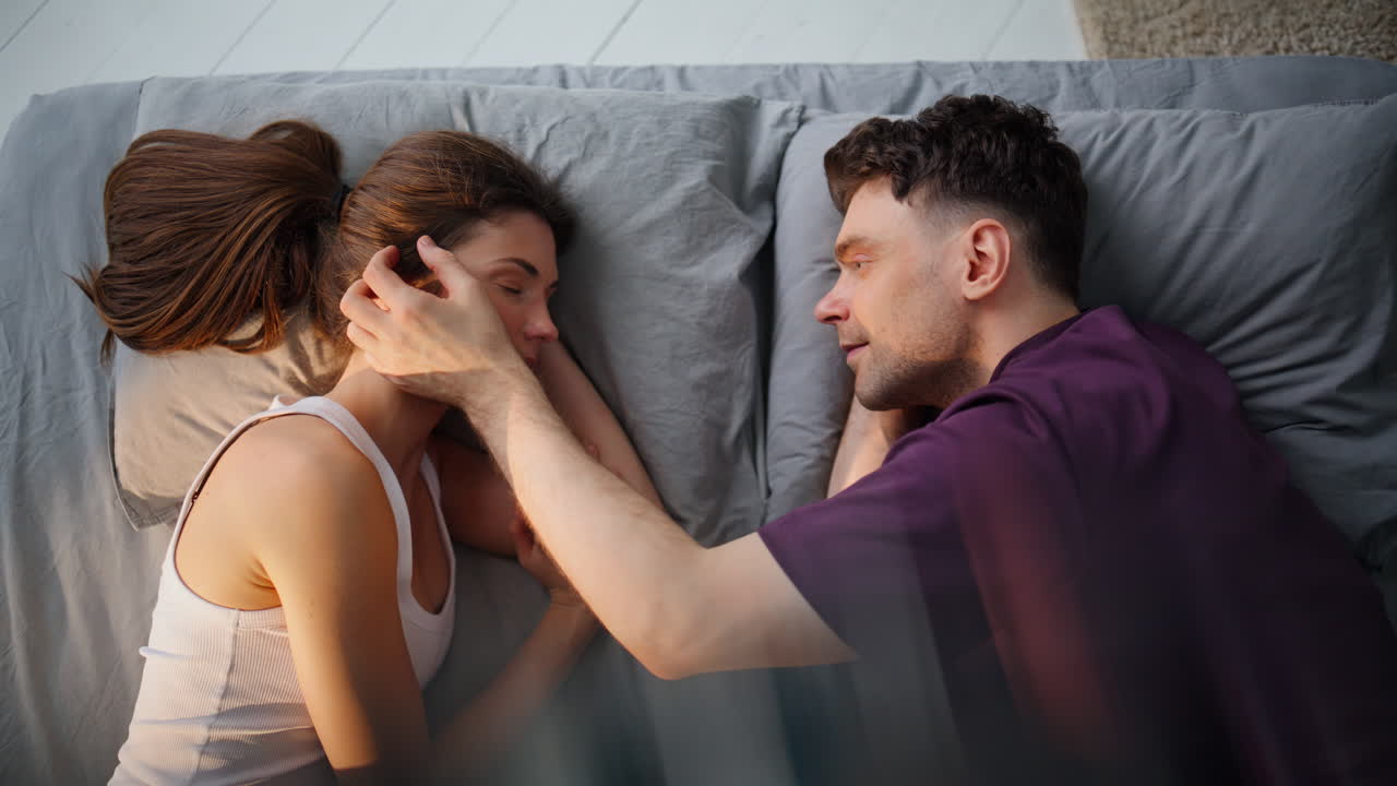 Primo piano di una coppia innamorata che si accarezza a letto. Due amanti si svegliano comodamente.