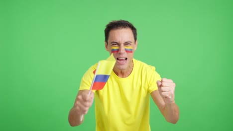 man cheering for colombia screaming and waving a national flag