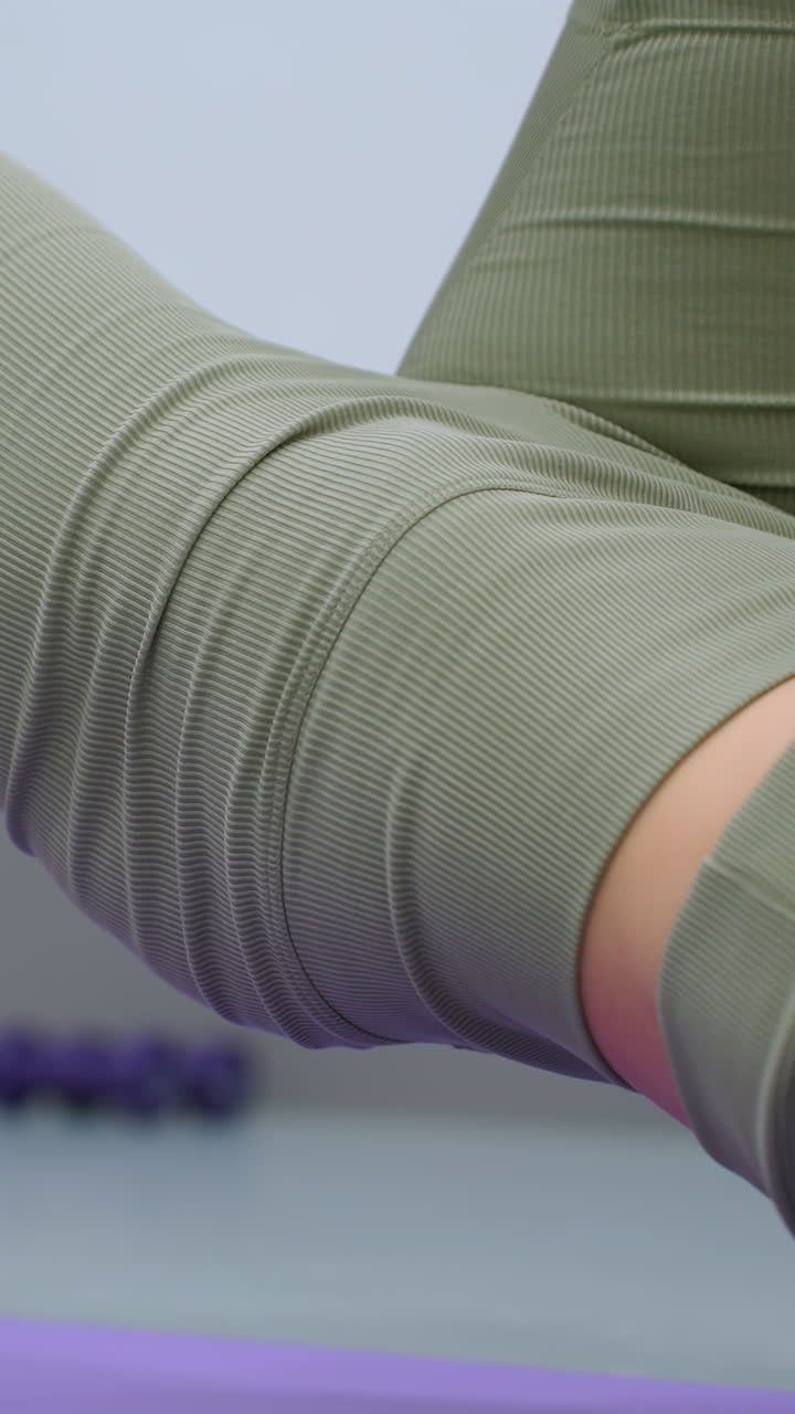 primer plano de una mujer con ropa deportiva verde que se eleva ligeramente mientras hace ejercicio, fondo borroso con el sofá, centrándose en el fitness y el movimiento del cuerpo en el gimnasio en casa