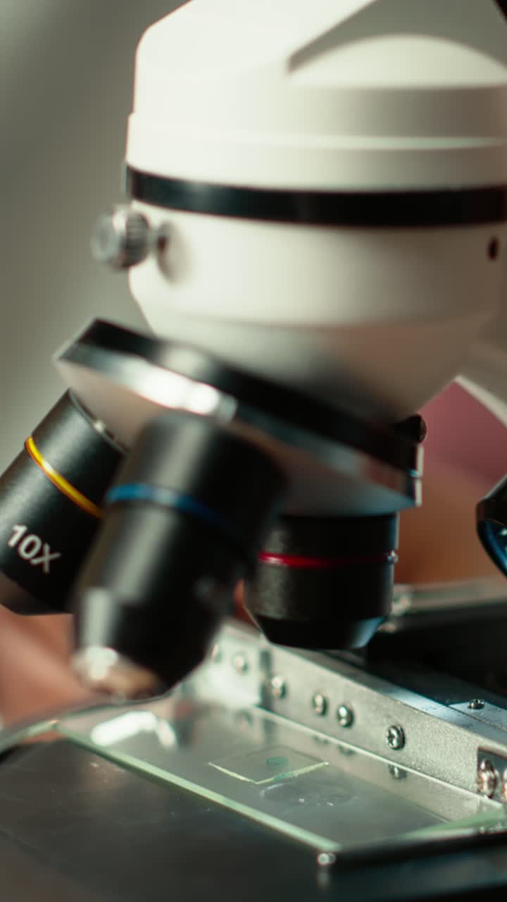 Close-up of Scientist's Hand Placing Slide Under Microscope