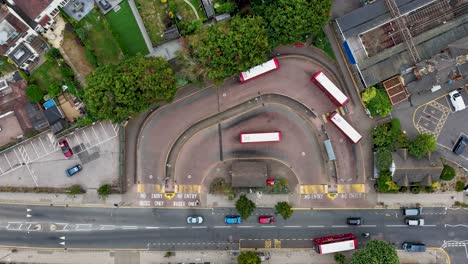 aerial top-down timelapse over bus station showing buses, trains, and cars arriving and departing, with the bus depot, train station, and car park all visible in one busy urban transport hub scene