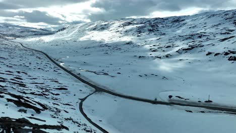 Strynefjellet-Mountain-Road-RV-15-in-Breiddalen-valley-at-sunny-spring-day-with-still-snow-left-in-the-hills---Aerial-showing-intersection-with-old-road-FV-63-to-Geiranger---Aerial