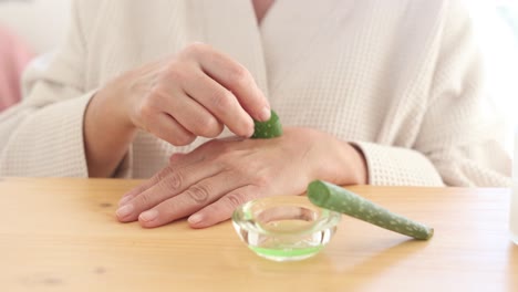 unrecognizable woman rubbing hand with aloe vera