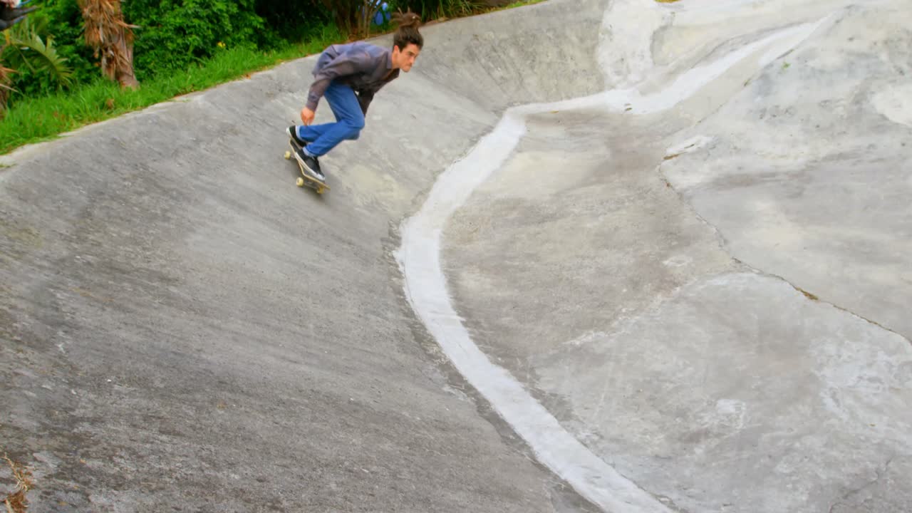 vista lateral de un joven caucásico practicando patinaje en una rampa en un parque de patinaje 4k