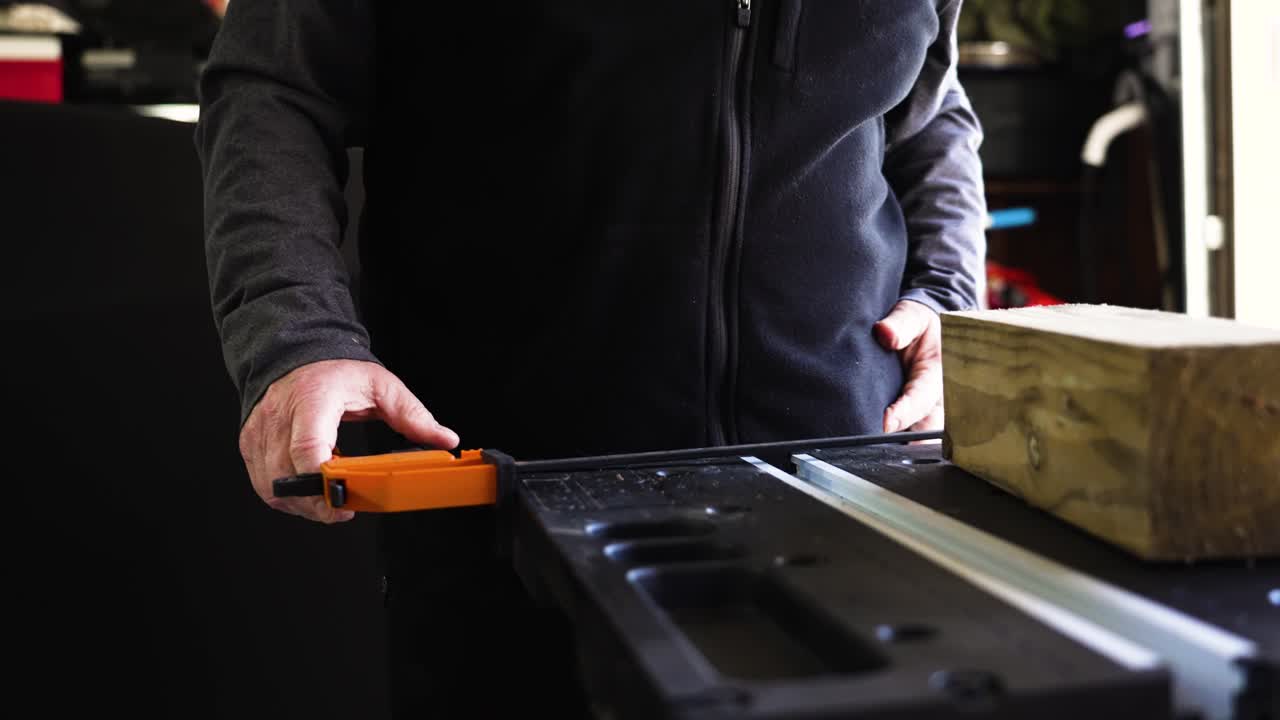 clip en cámara lenta de un hombre ajustando una mesa de trabajo con un poste de madera en la mesa