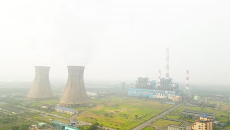 aerial view of industries in india, showcasing smoke-emitting chimneys against an urban backdrop.