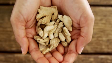 Hands-holding-dried-ginger-against-wooden-table-4k