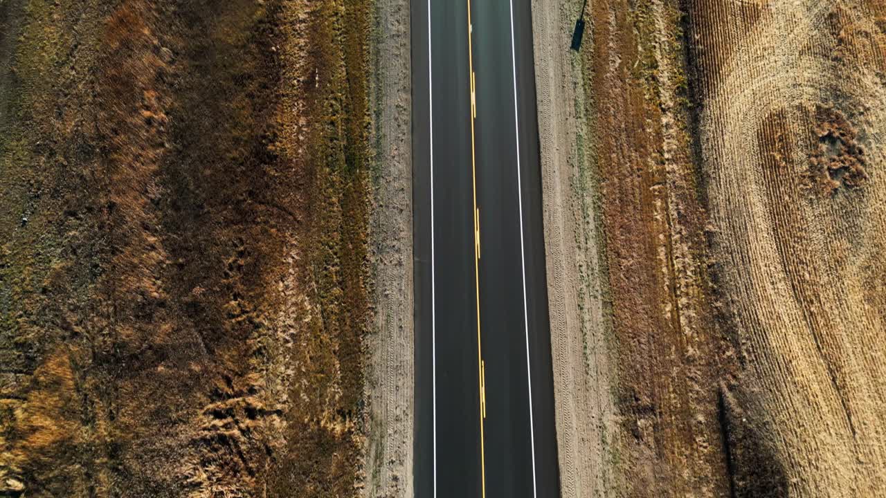 Ripresa aerea dall'alto di un lungo viale di campagna tra campi agricoli aridi durante la stagione autunnale, Francis, provincia di Saskatchewan, Canada