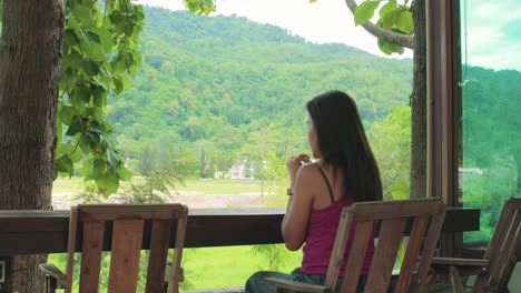 outdoor coffee shop with a beautiful thai lady sitting down at a bar drinking soda overlooking a scenic view of khao yai national park