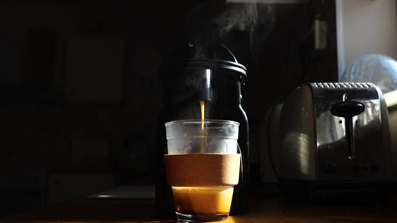 video de una máquina de café expreso humeante que fluye en una taza de vidrio