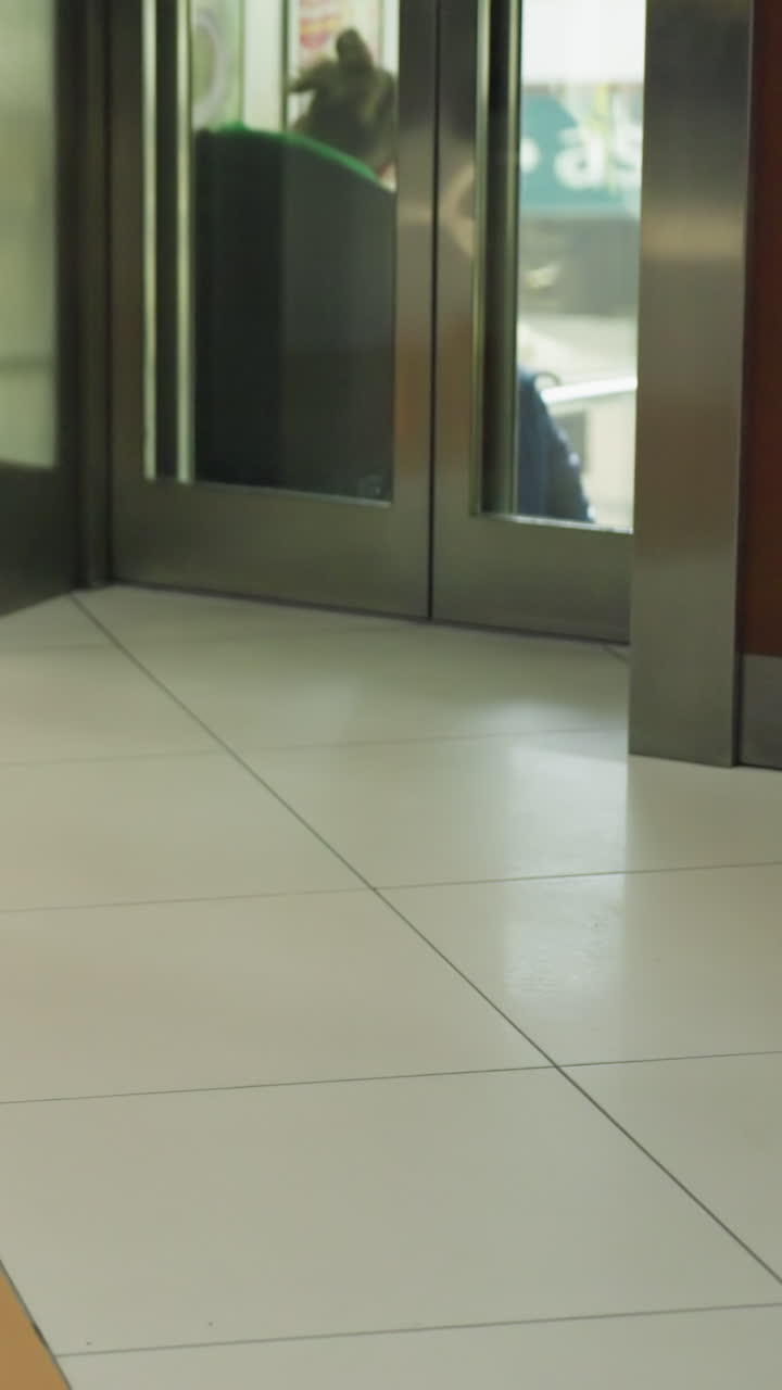 el enfoque está en un ascensor con personas dentro, descendiendo. la imagen incluye a una persona en primer plano alejándose, destacando el entorno dinámico del centro comercial