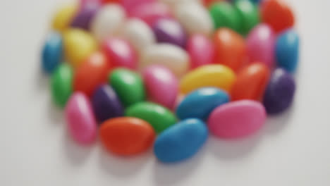 video of close up of multi coloured sweets forming circle over white background