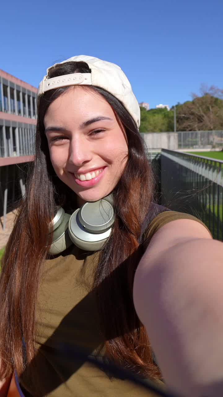Giovane donna che sorride e fa l'occhiolino in un video selfie nel campus